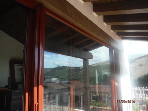 Custom painted and made Mahogany brown/brick retractable screen doors installed on the outside of the front view bi-folding doors for quick ventilation